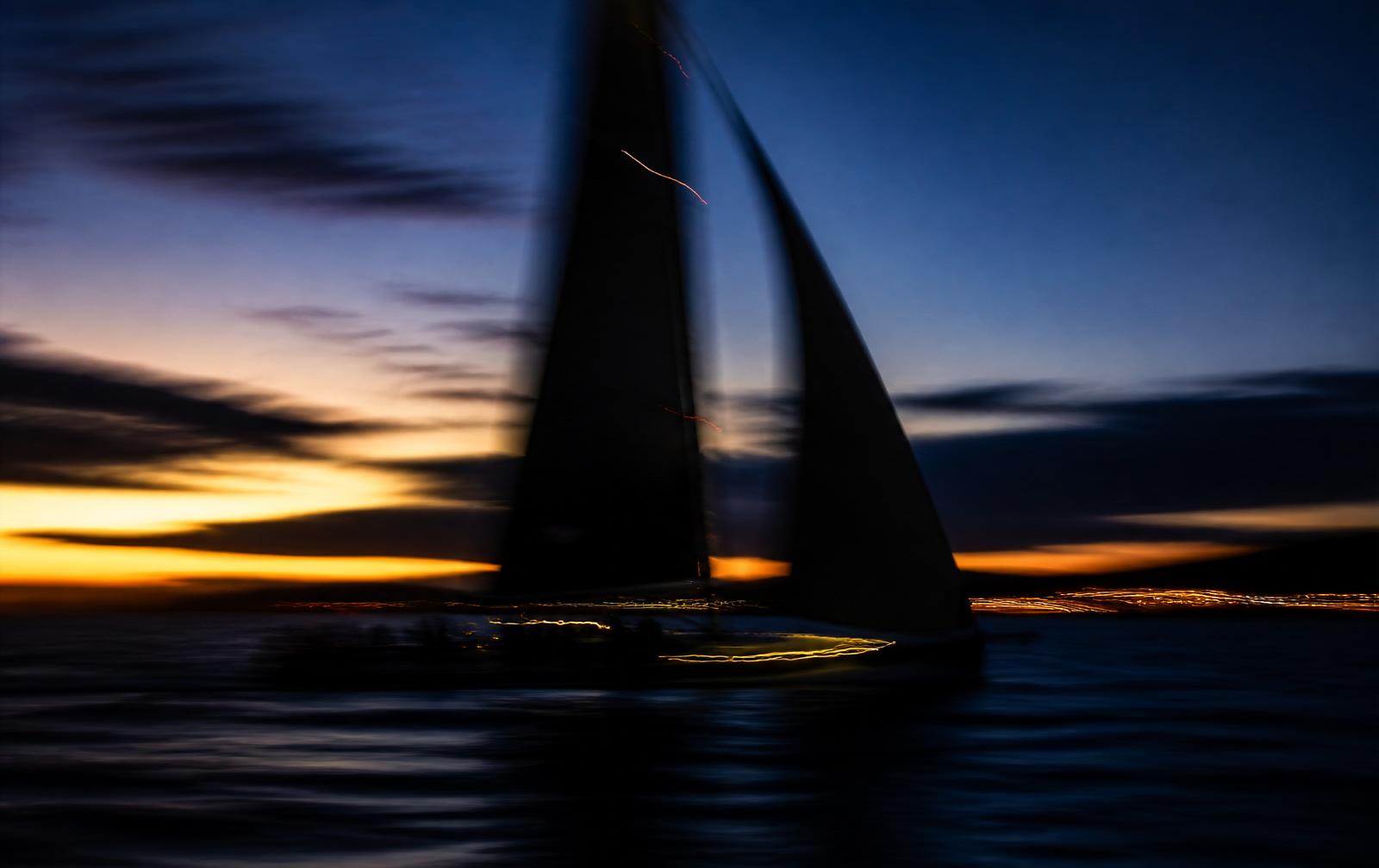 Talentzo Racing — sailboat under sail at dusk with motion blur and warm light